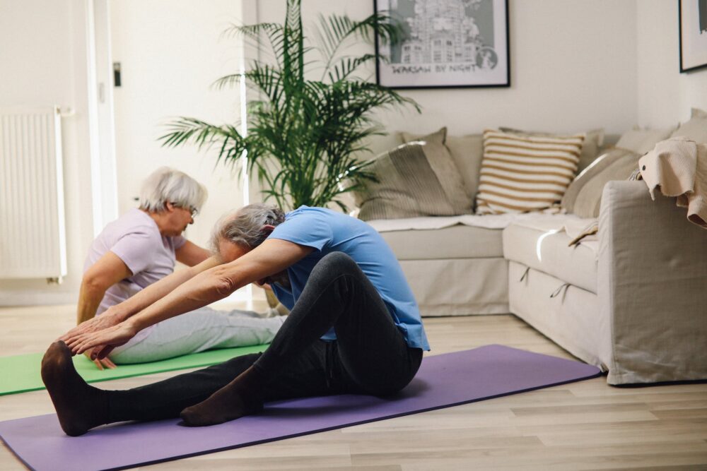 A Couple Sitting on Yoga Mats Stretching Forward